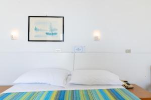 a bed with white pillows and a picture on the wall at Hotel Concord in Lido di Savio