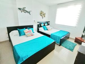 a bedroom with two beds with blue sheets and a window at Apartamento 802 Brisas marinas Santa Marta COLOMBIA in Santa Marta