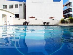 a swimming pool with tables and umbrellas on a building at Apartamento 802 Brisas marinas Santa Marta COLOMBIA in Santa Marta +8 photos