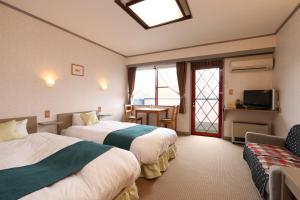 um quarto de hotel com duas camas e um sofá em Naughty Cao em Yamanakako