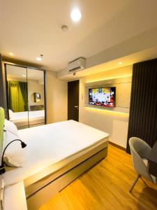 - une chambre avec un grand lit et une télévision murale dans l'établissement 2 kamar Amarta apartemen By Tempattinggaljog, à Kejayan