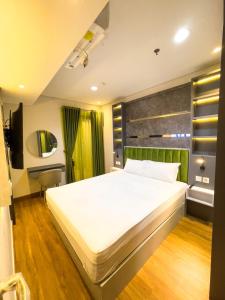 - une chambre avec un lit blanc et une tête de lit verte dans l'établissement 2 kamar Amarta apartemen By Tempattinggaljog, à Kejayan