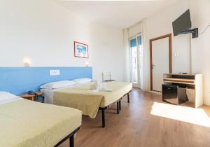 a hotel room with two beds and a television at Hotel Concord in Lido di Savio