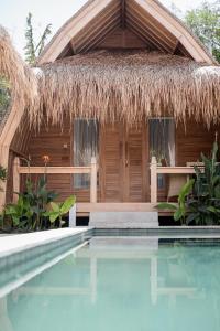 ein Resort mit einem strohgedeckten Gebäude und einem Pool in der Unterkunft My Island Home Gili Air in Gili Air