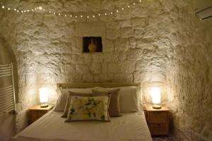 una camera da letto con un muro in pietra, un letto e 2 lampade di Terre d'amore - For couples a Ostuni