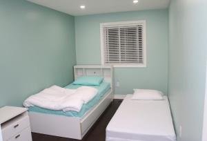 een blauwe kamer met 2 bedden en een raam bij Quiet and Contemporary Home in Markham