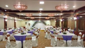 a banquet hall with white tables and chairs and chandeliers at The Rialto Hotel in Bengaluru
