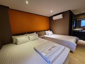 a bedroom with two beds and a bathroom with a sink at Foxy Hotel in Busan