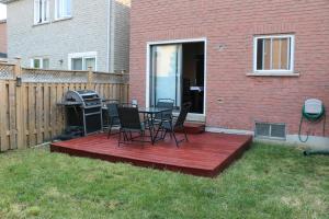 a deck with chairs and a grill in a yard at Quiet and Contemporary Home in Markham