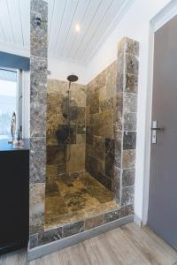a bathroom with a shower with a stone wall at Villa LAtibulum in Saint-Pierre