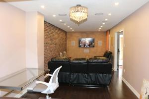 a living room with a black leather couch and a chandelier at Quiet and Contemporary Home in Markham