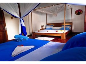 a bedroom with a canopy bed with blue sheets at VILLA AMNESYA NOSY BE in Nosy Be +56 photos