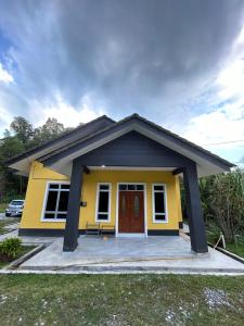 uma casa amarela com um telhado preto em Teratak Cikgu Din em Marang