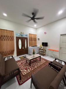 uma sala de estar com um sofá e uma ventoinha de tecto em Teratak Cikgu Din em Marang