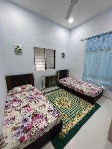 a bedroom with two beds and a window at Teratak Cikgu Din in Marang