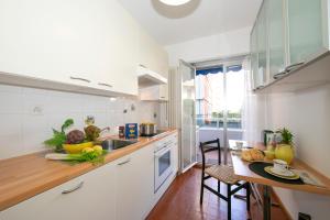 a kitchen with white cabinets and a table with fruit on it at Pool House - Happy Rentals in Lugano