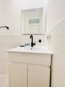 a white bathroom with a sink and a mirror at Underground in Tel Aviv