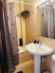 La salle de bains est pourvue d'un lavabo blanc et d'une douche. dans l'établissement Right by the pool area in Capistrano Village!, à Nerja