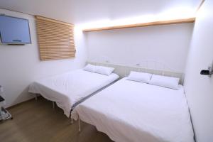 ソウルにあるAll Stay Inn Seoulのベッド2台、壁掛けテレビが備わる客室です。