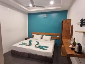 a bedroom with a bed with two swans on it at Tavern Lodge Maafushi in Maafushi