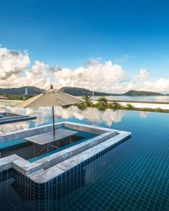 Andamantra Resort and Villa Phuket - SHA Extra Plus في شاطيء باتونغ: المسبح مع مظله والماء