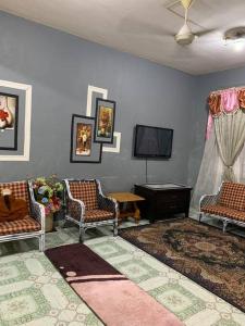 uma sala de estar com 2 cadeiras e uma televisão de ecrã plano em GayaMas Homestay em Sandakan