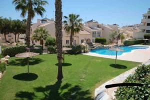 a resort yard with a swimming pool and palm trees at La casa de Lucas in Orihuela Costa