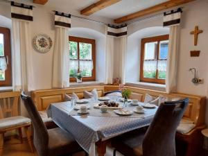 comedor con mesa, sillas y ventanas en Gschwandnerhof, en Michelsneukirchen