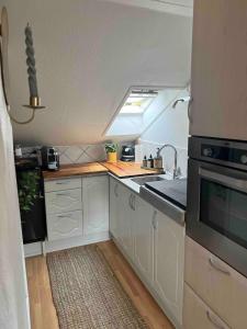 uma cozinha com armários brancos, um lavatório e um fogão em Cozy City apartment em Holbæk