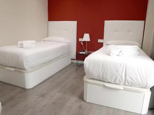 1 dormitorio con 2 camas con sábanas blancas en Apartamentos Royal Urban Granada, en Granada