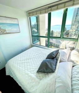 a bedroom with a white bed with a large window at Stunning ocean (sound of waves) in Vancouver
