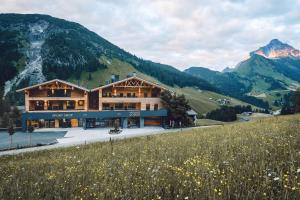 a chalet in the mountains with a field of flowers at Lech Valley Lodge in Warth am Arlberg