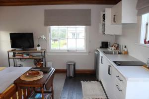 オークランドにあるThe Studio - Huntly Houseのキッチン(シンク、テーブル付)、窓が備わります。