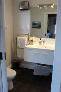 a bathroom with a sink and a toilet and a mirror at The Studio - Huntly House in Auckland