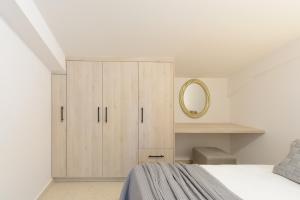 a white bedroom with a bed and a mirror at Zissis Suites Downtown Apartment in Zakynthos Town