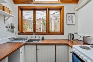 Adorable 1855 cottage - South Hobart Village في هوبارت: مطبخ مع حوض ونافذة