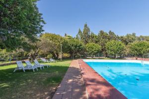 una piscina con 2 sillas blancas y árboles en Home2Book Villa El Naranjo, Garden & Pool, en Valsequillo