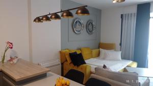 a living room with a bed and a yellow couch at The Impressive Apartment in Trebinje
