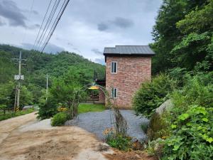a brick building on the side of a dirt road at Samhyeongjebonggil Pension in Gangneung