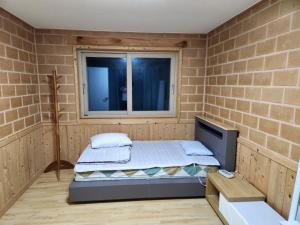 een slaapkamer met een bed in een bakstenen muur bij Samhyeongjebonggil Pension in Gangneung