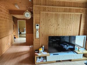 a living room with a large flat screen tv at Samhyeongjebonggil Pension in Gangneung