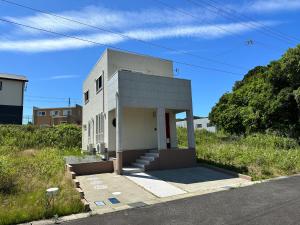 un petit bâtiment blanc sur le côté d'une route dans l'établissement 白浜貸別荘ss2-88, à Shirahama