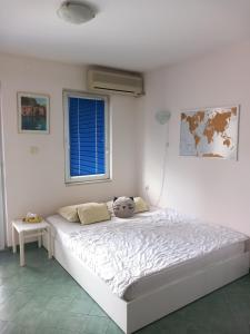 a white bedroom with a bed with a stuffed animal on it at Apartment Budva in Budva