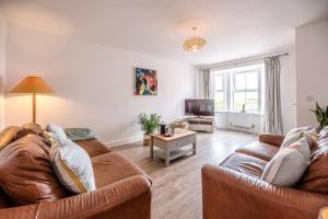 een woonkamer met twee bruine banken en een tv bij Spindrift, Felixstowe in Felixstowe