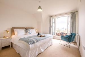 een slaapkamer met een bed, een stoel en een raam bij Spindrift, Felixstowe in Felixstowe