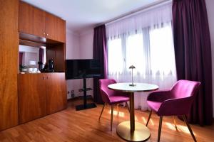 ein Wohnzimmer mit einem Tisch und rosa Stühlen in der Unterkunft Le Cinéma - Affittacamere in Formia