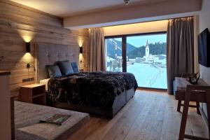 a bedroom with a bed and a large window at Lech Valley Lodge in Warth am Arlberg