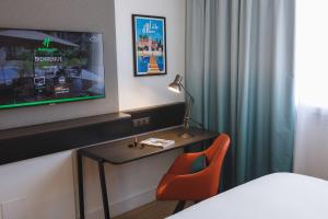 a hotel room with a bed and a desk with a television at Holiday Inn Toulon City Centre, an IHG Hotel in Toulon