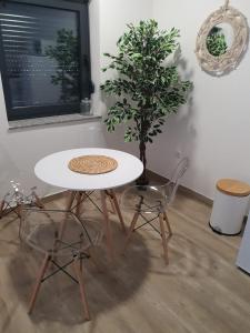 une table et des chaises dans une pièce avec une plante dans l'établissement Apartman SIMON-CENTAR, à Nova Gradiška