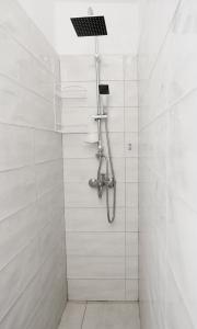 ein Bad mit einer Dusche und weißen Fliesen in der Unterkunft Matias sweetest home in Tirana